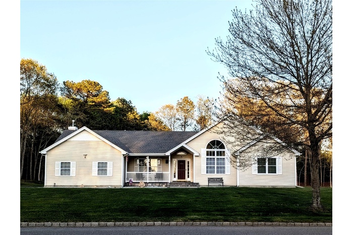 Ranch-style home featuring a front lawn and covered porch