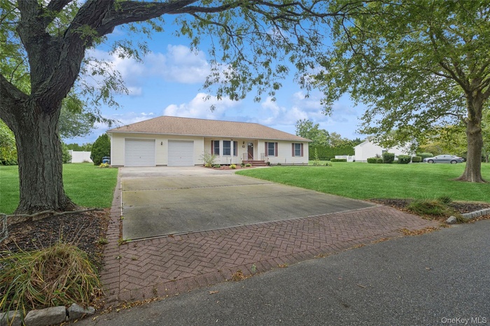 Single story home featuring decorative driveway, a front lawn, a garage, and covered porch
