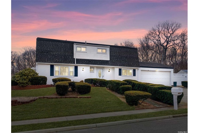 View of front of property with roof with shingles, a garage, and a lawn
