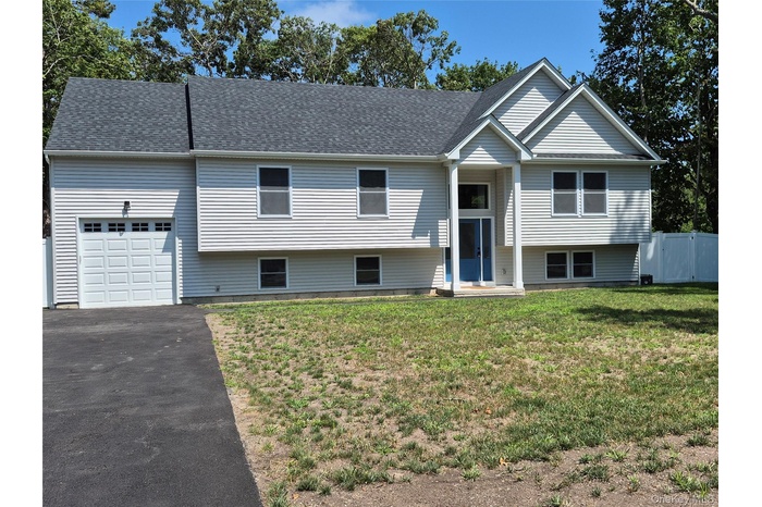 Split foyer home featuring a garage, asphalt driveway, and roof with shingles