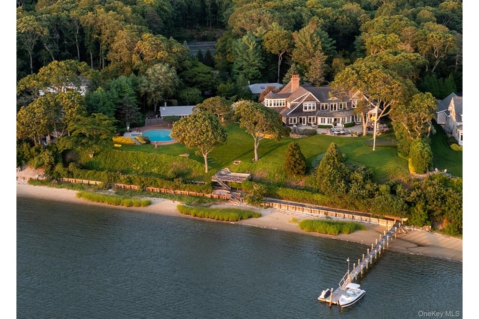 Aerial overview of property's location with a nearby body of water and a heavily wooded area
