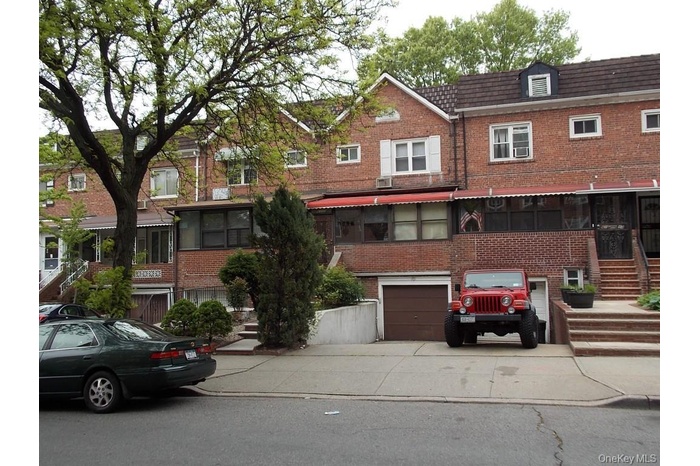 View of front of home with brick siding, driveway, and a garage