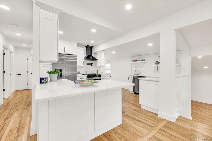 Kitchen featuring a peninsula, white cabinetry, recessed lighting, tasteful backsplash, and appliances with stainless steel finishes