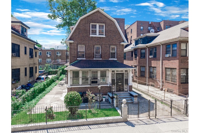 View of front of home with a gambrel roof, brick siding, and a fenced front yard