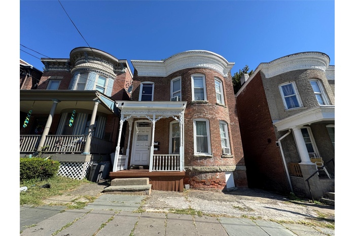 Victorian-style house featuring brick siding and a porch