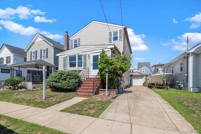 View of front of house featuring a detached garage, an outdoor structure, driveway, and a front yard