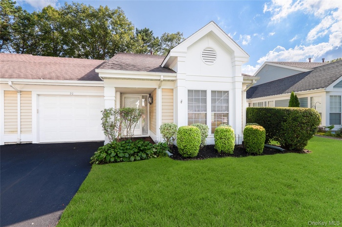 Neoclassical / greek revival house with a garage, driveway, a front lawn, and a shingled roof