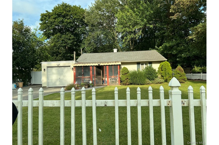 View of front of home featuring a fenced front yard, a sunroom, an attached garage, driveway, and roof with shingles