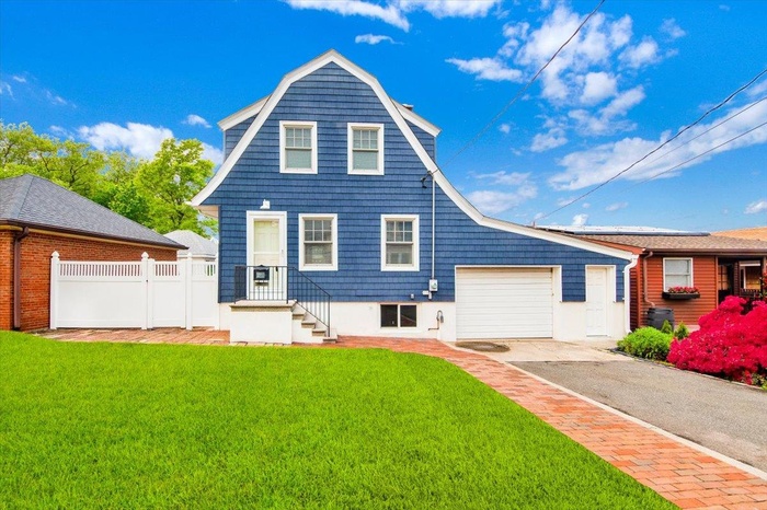 View of front of home with driveway, a garage, and a gambrel roof