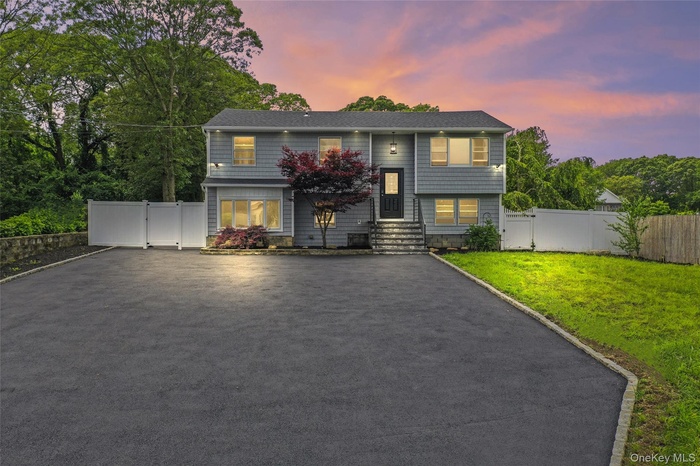 Bi-level home featuring a gate and asphalt driveway