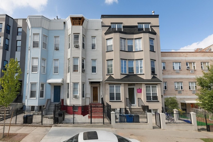 View of building exterior featuring entry steps and a fenced front yard