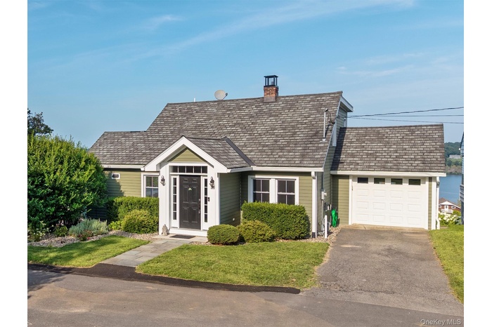 View of front of property with an attached garage, asphalt driveway, a chimney, and a front yard