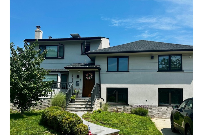 View of front of home with a chimney, stucco siding, and roof with shingles