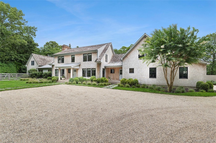 View of front facade featuring covered porch, a chimney, and driveway