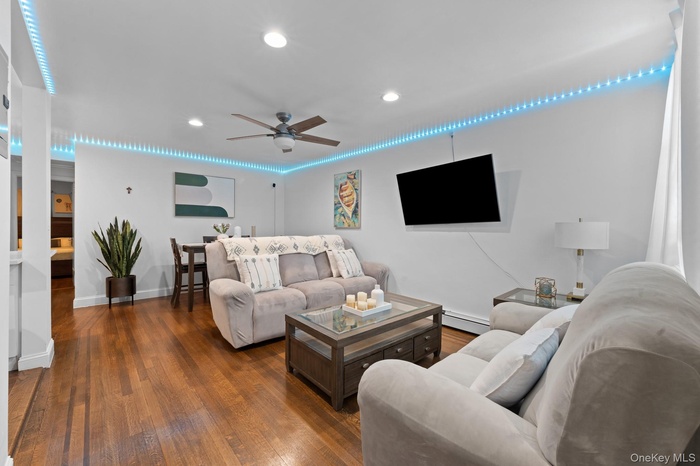 Living room featuring ceiling fan, dark wood-type flooring, recessed lighting, and a baseboard heating unit