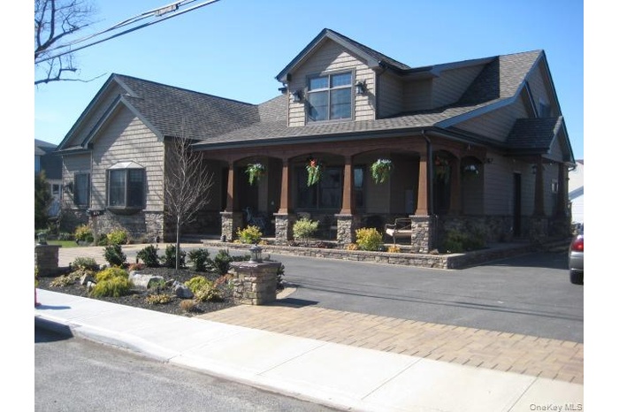 Craftsman house with a porch, stone siding, and a shingled roof