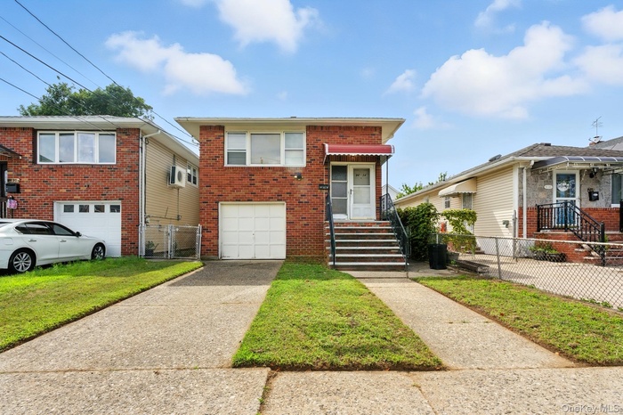 View of front of property with an attached garage, driveway, brick siding, and a front lawn