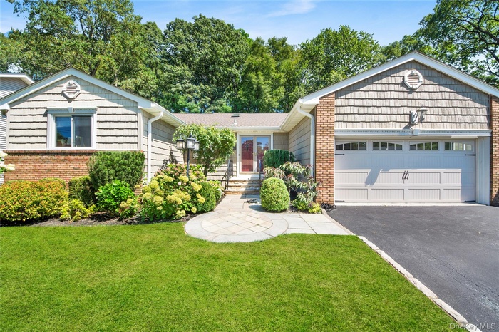 Ranch-style house with driveway, a garage, and a front lawn