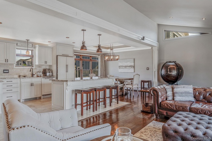 Living area with a chandelier, healthy amount of natural light, light wood-style floors, recessed lighting, and crown molding