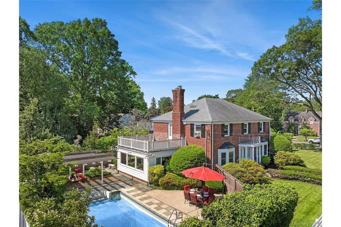 Back of house featuring a balcony, a chimney, an outdoor pool, a patio area, and new shingled roof