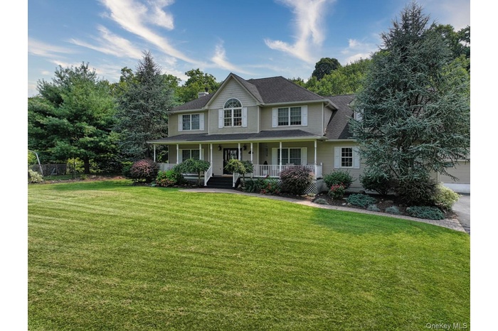 Colonial inspired home featuring covered porch, a large, front lawn, and roof with solar panels (owned)