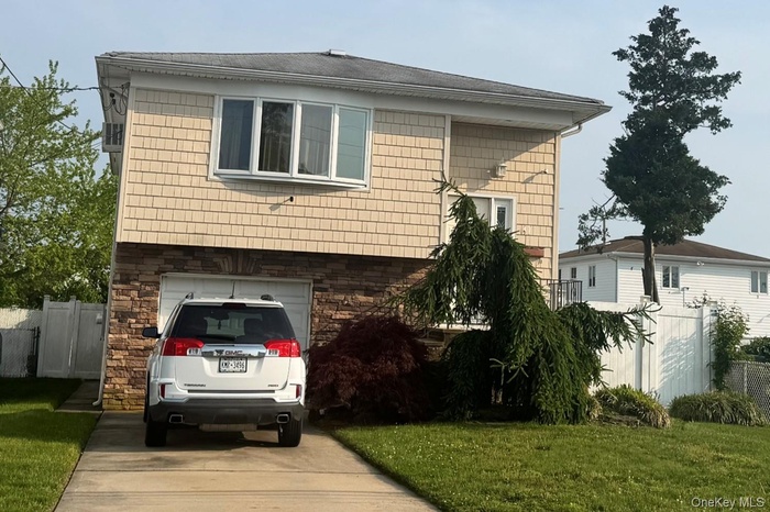 View of side of property with a garage, concrete driveway, and stone siding