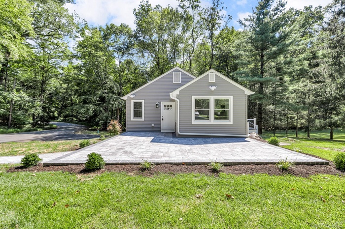 Back of house with a patio area, view of wooded area, and a yard