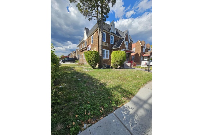 View of side of property with brick siding, a residential view, and a lawn