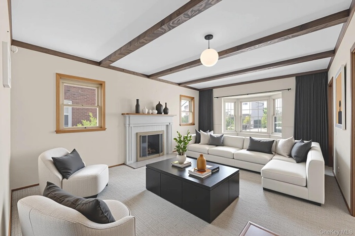 Living room featuring beam ceiling, a glass covered fireplace, and carpet