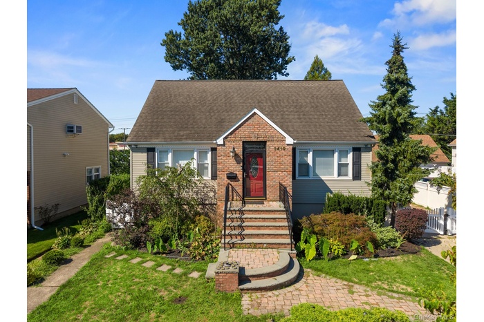 View of front of home featuring a shingled roof, a front lawn, and brick siding