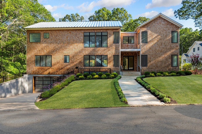 View of front of house featuring an attached garage, driveway, a front lawn, and a metal roof