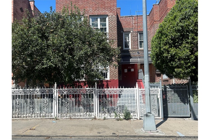 View of front of house featuring brick siding, a fenced front yard, and a gate