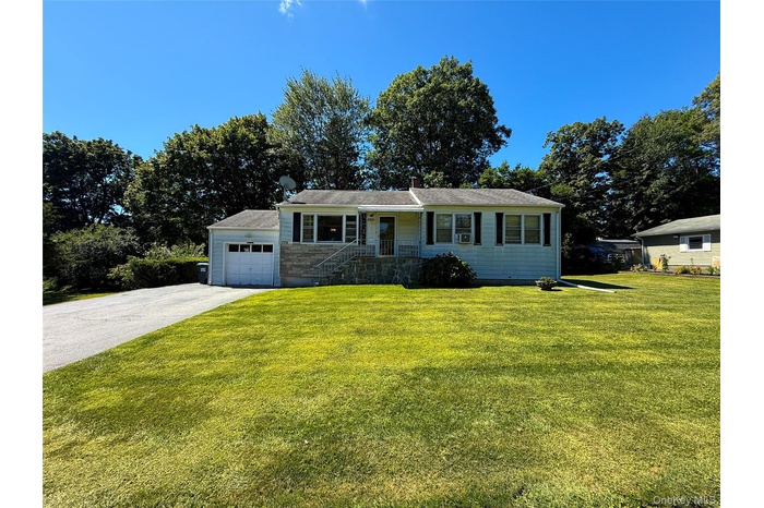 Single story home featuring a front lawn, a garage, asphalt driveway, and covered porch