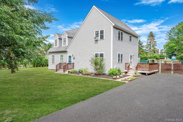 View of side of home featuring a shingled roof, a yard, and a wooden deck