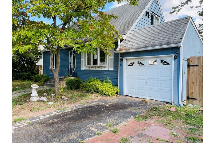 View of front of property featuring a garage, roof with shingles, and asphalt driveway