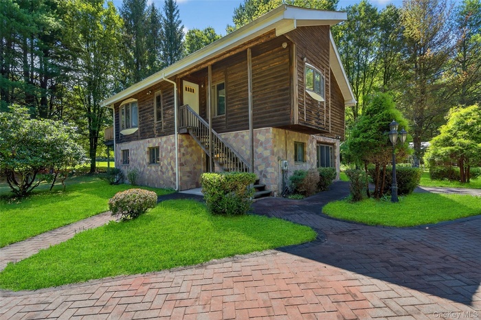 Chalet / cabin featuring stone siding, stairway, a front yard, and covered porch