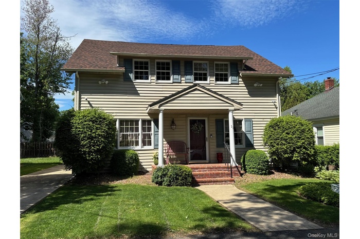 View of front of property featuring a front lawn, a shingled roof, and a porch