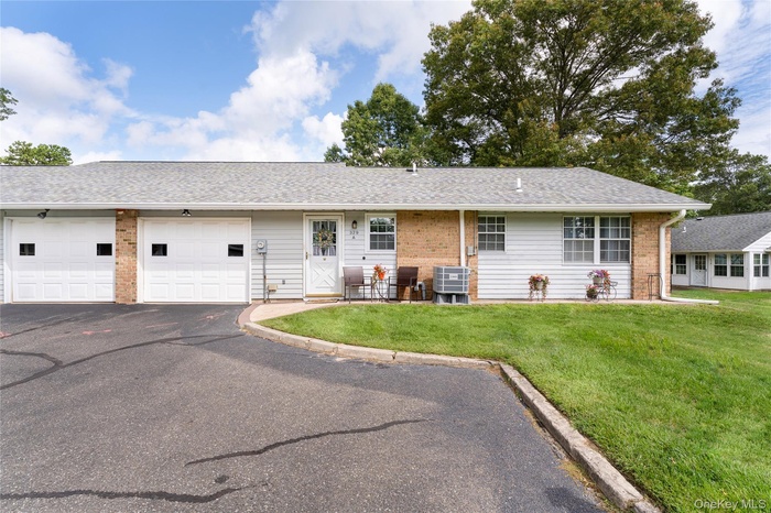 Ranch-style house with brick siding, a shingled roof, asphalt driveway, and a front yard