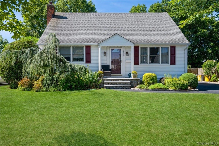 View of front facade with a chimney, a front lawn, and a shingled roof