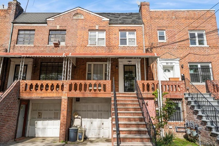 Traditional-style home with stairs, an attached garage, and brick siding