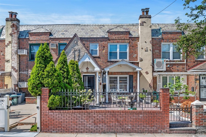 View of front of home featuring brick siding, a fenced front yard, a high end roof, and a chimney