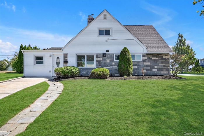 View of front of home featuring a front yard, roof with shingles, a chimney, and stone siding