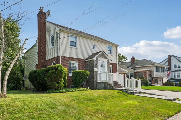 Colonial house featuring brick siding, a front lawn, and a chimney
