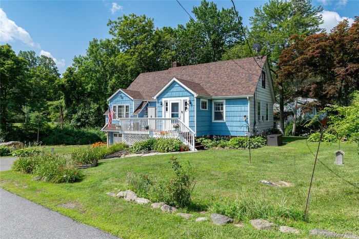 View of front of home featuring a shingled roof, a front yard, and a chimney