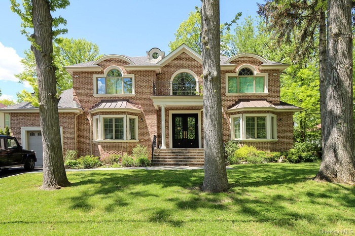View of front facade with french doors, brick siding, a front yard, and a garage