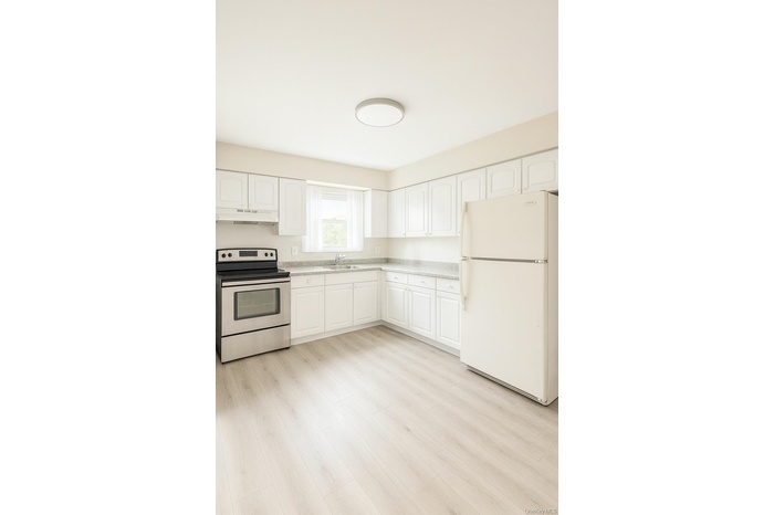 Kitchen featuring freestanding refrigerator, stainless steel electric range, white cabinetry, light wood finished floors, and under cabinet range hood