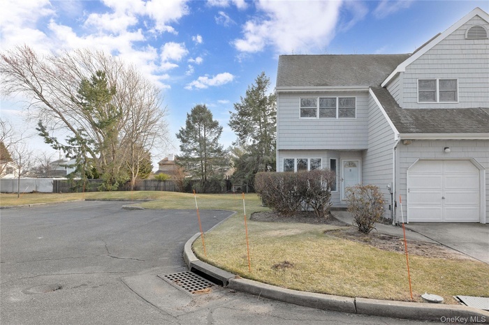 View of side of property with aphalt driveway, a lawn, roof with shingles, fence, and a garage