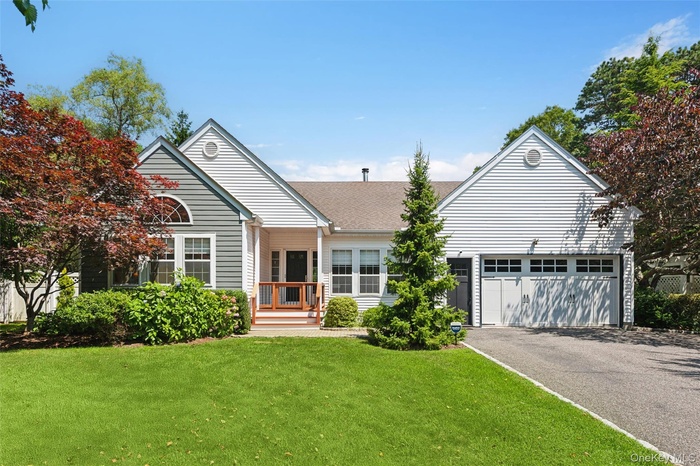 View of front of property featuring a front yard, driveway, a garage, and roof with shingles