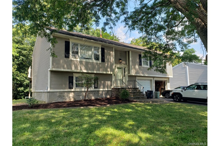 Split foyer home with a garage and a front yard