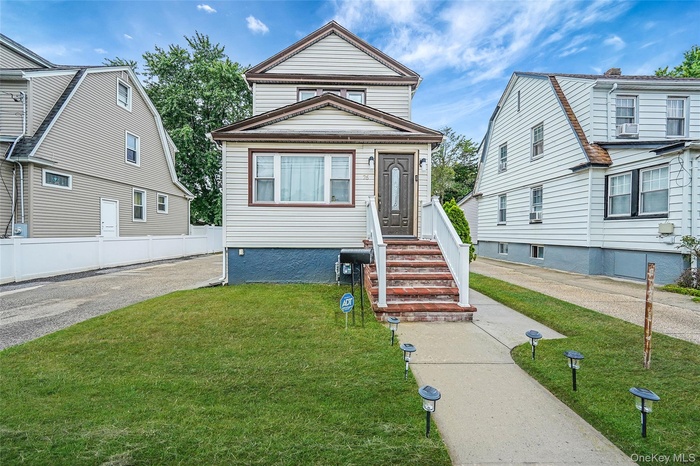 View of front facade featuring a front yard and cooling unit